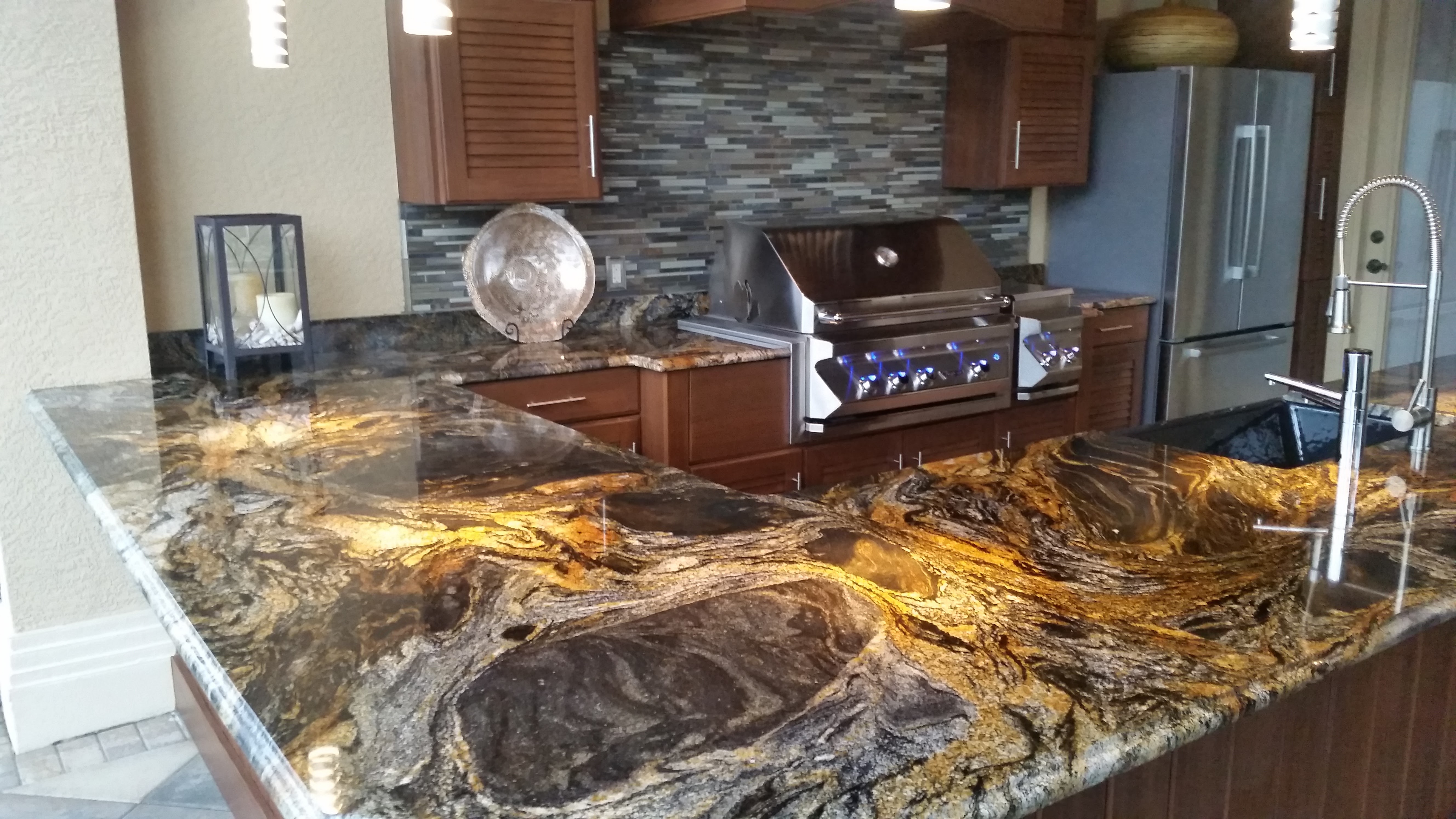 Custom outdoor kitchen with dramatic granite countertop and built-in grill